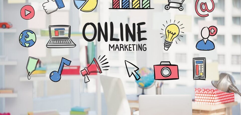 Escritorio moderno con una computadora portátil y elementos gráficos de marketing digital, incluyendo iconos de redes sociales, gráficos y herramientas de publicidad, con el texto "ONLINE MARKETING" destacado.