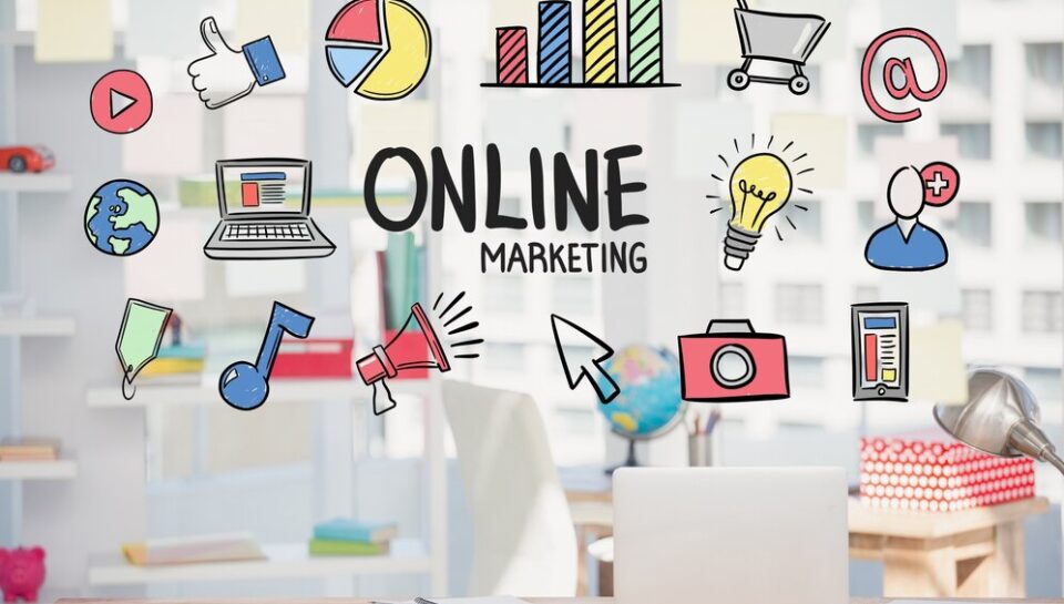 Escritorio moderno con una computadora portátil y elementos gráficos de marketing digital, incluyendo iconos de redes sociales, gráficos y herramientas de publicidad, con el texto "ONLINE MARKETING" destacado.